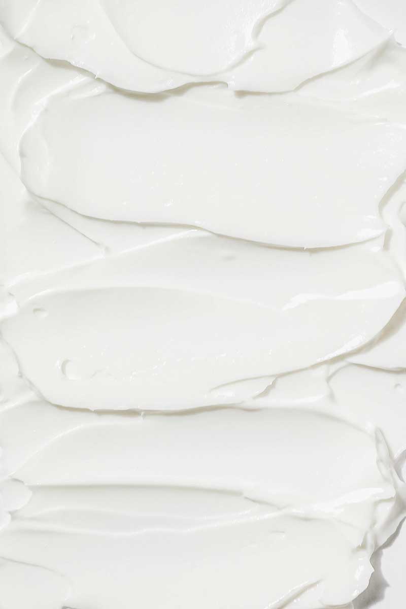 A textural image of a white skin care lotion spread out  in a similar way to a battered cake.